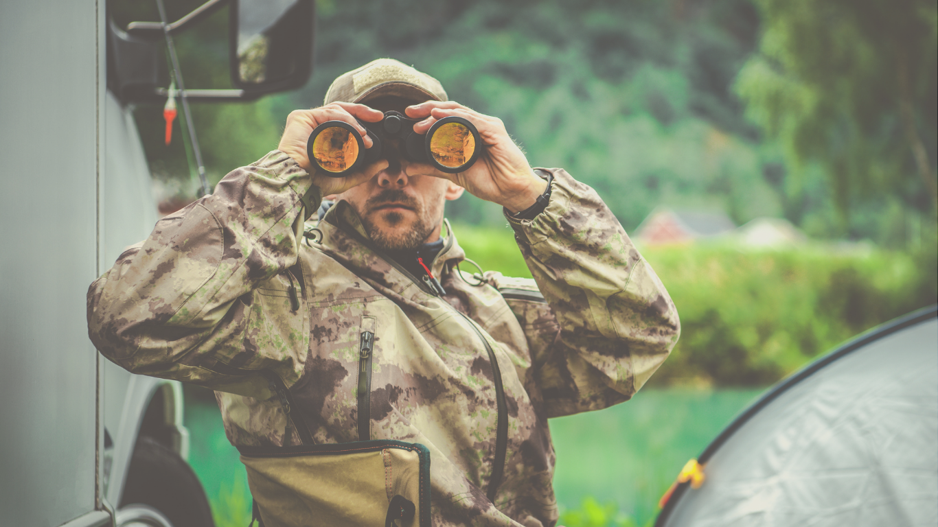 A man using binoculars at an off-grid RV campsite, capturing the adventurous side of RV boondocking and outdoor travel.